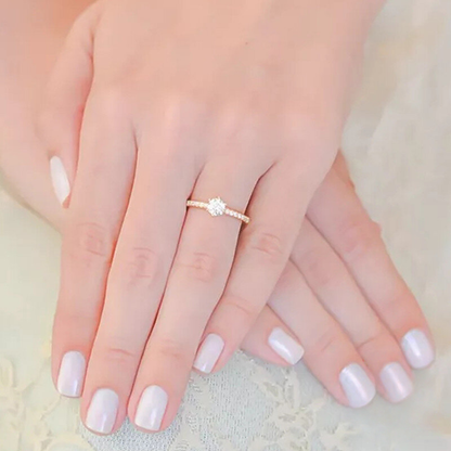 Hand wearing a gold ring with a diamond on a soft background