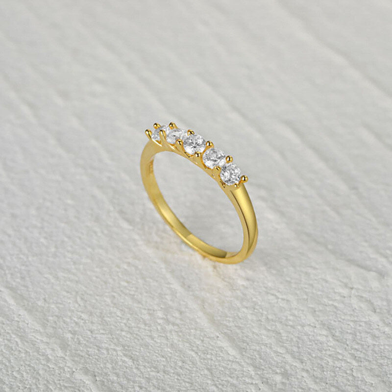 Gold ring with diamonds on a light gray textured background