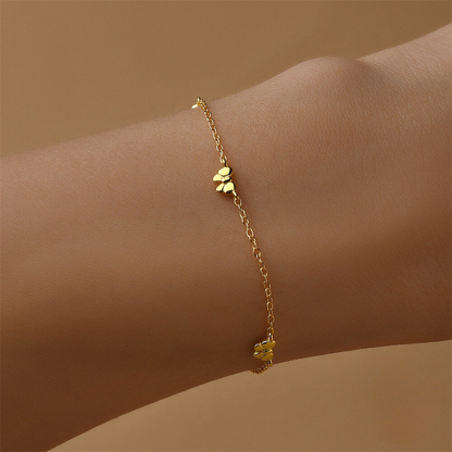 Gold bracelet with floral charms on a wrist against a beige background
