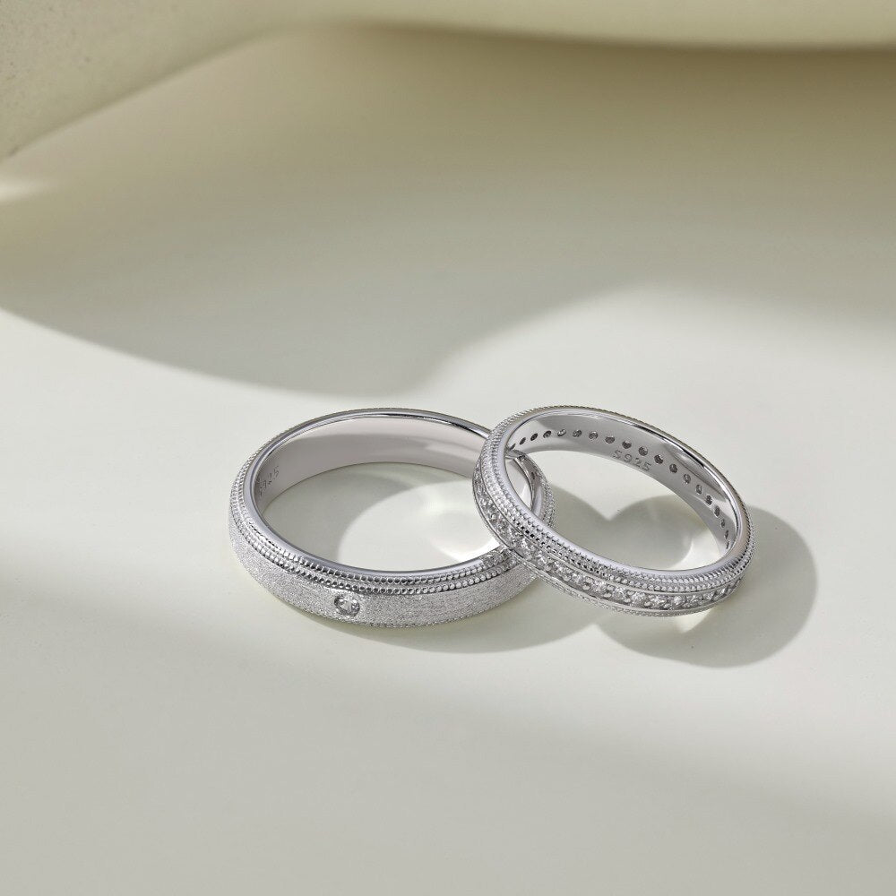 Two silver rings with intricate designs on a light beige background