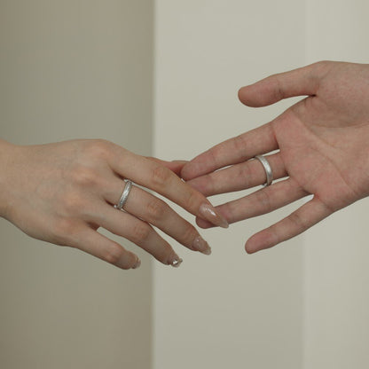 Two hands with silver rings on a neutral background