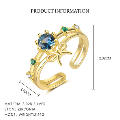 Gold ring with blue gemstone and green stones, featuring measurements and material details.