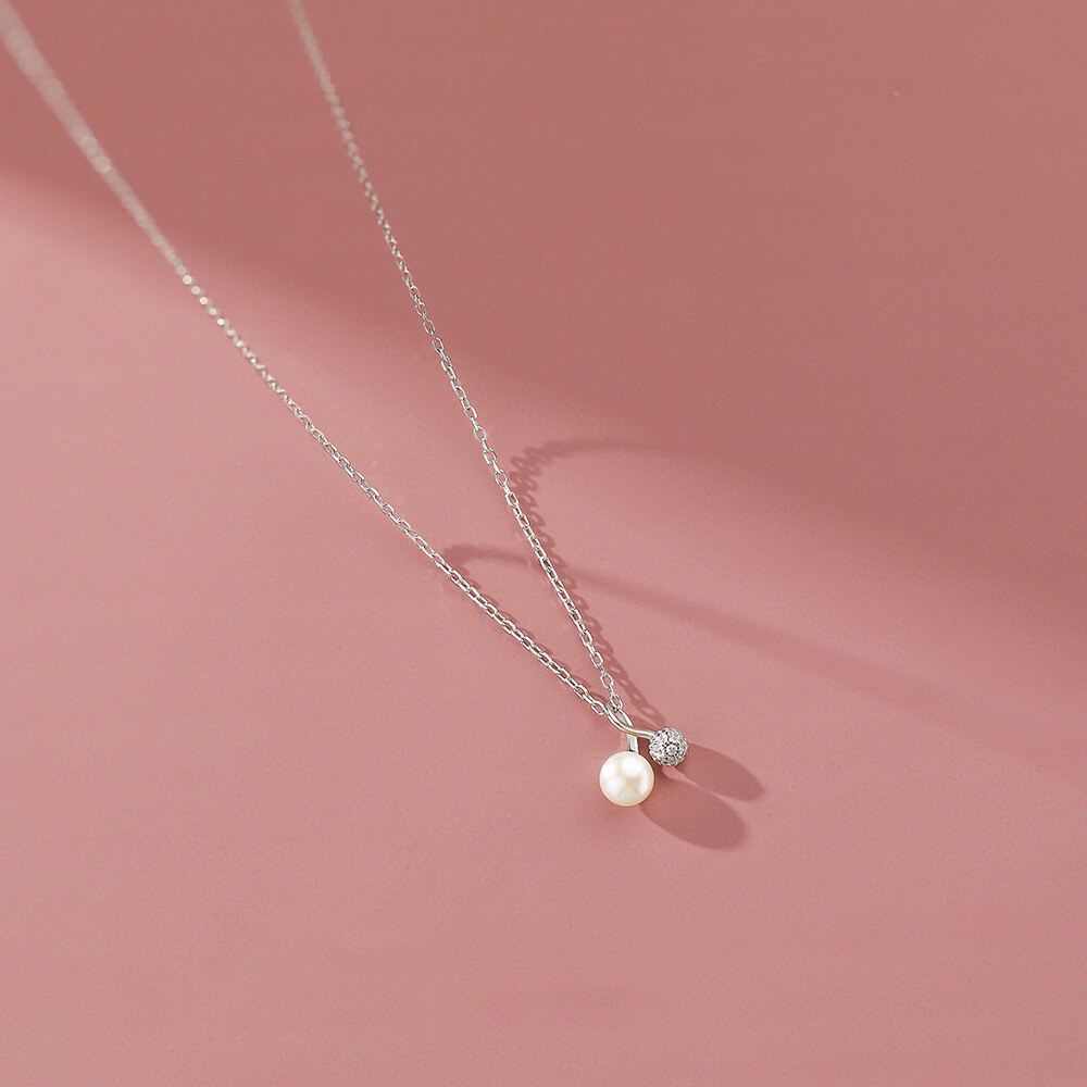 Pearl necklace with a silver chain on a pink background