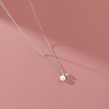 Pearl necklace with a silver chain on a pink background