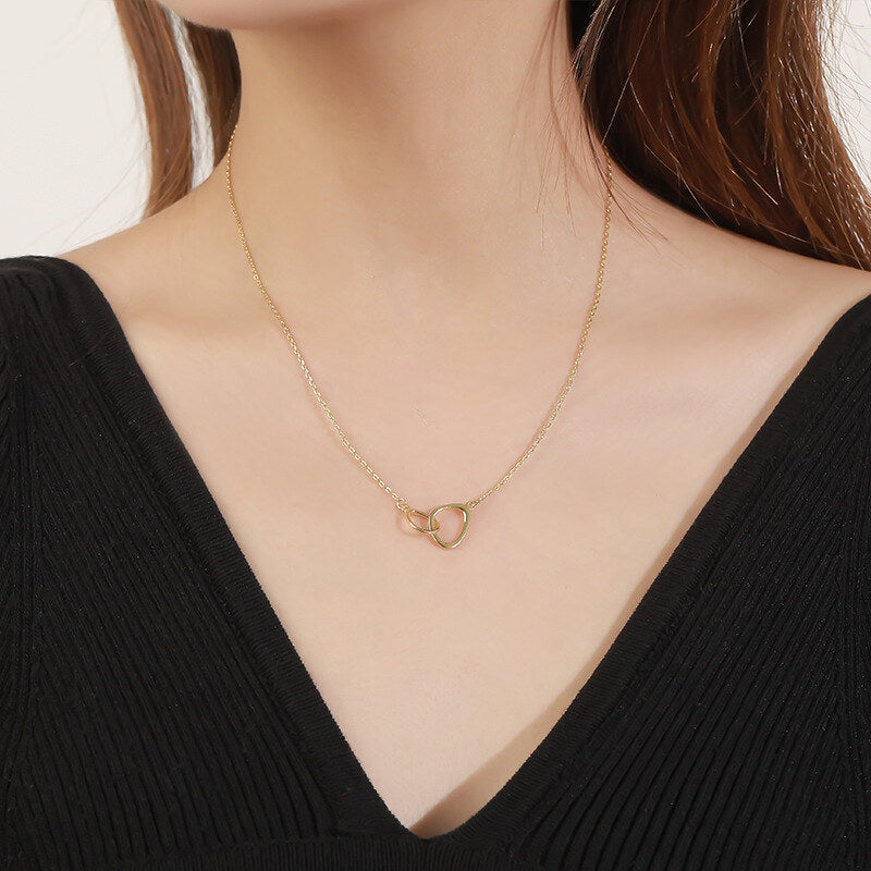 Gold necklace with a heart pendant worn by a person in a black top.