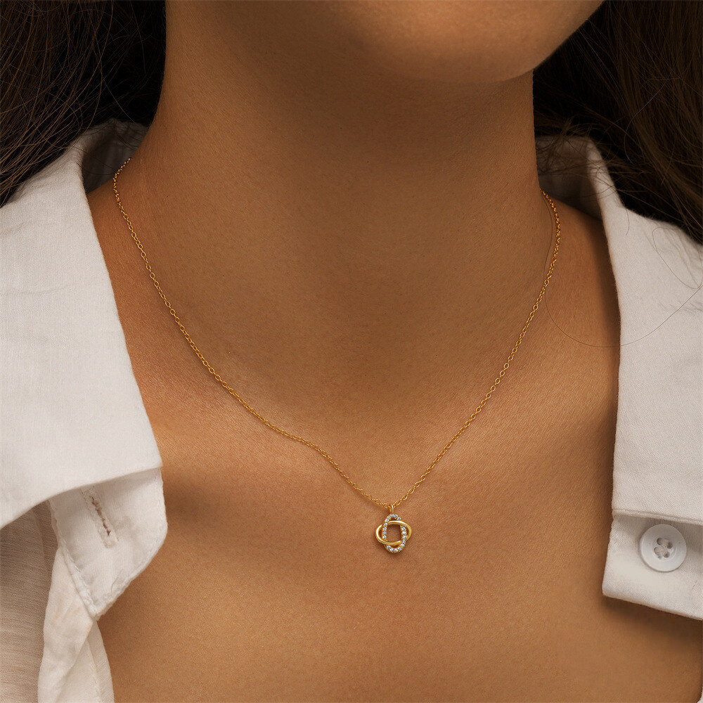 Gold necklace with a heart pendant on a person wearing a white shirt.