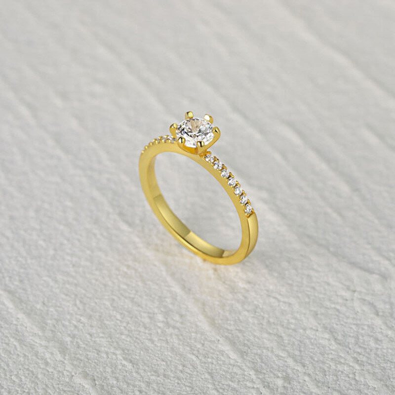 Gold ring with a diamond on a textured gray background