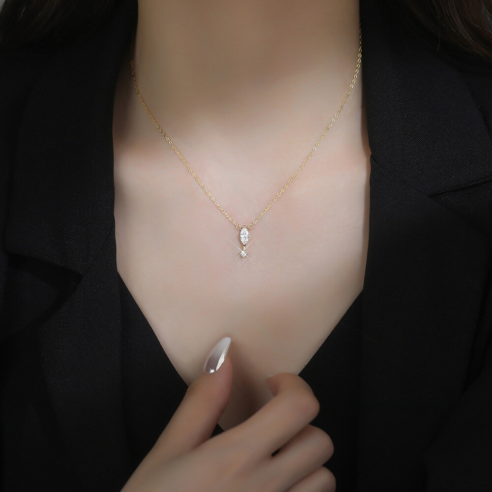 Necklace with a teardrop-shaped pendant worn by a person against a dark background