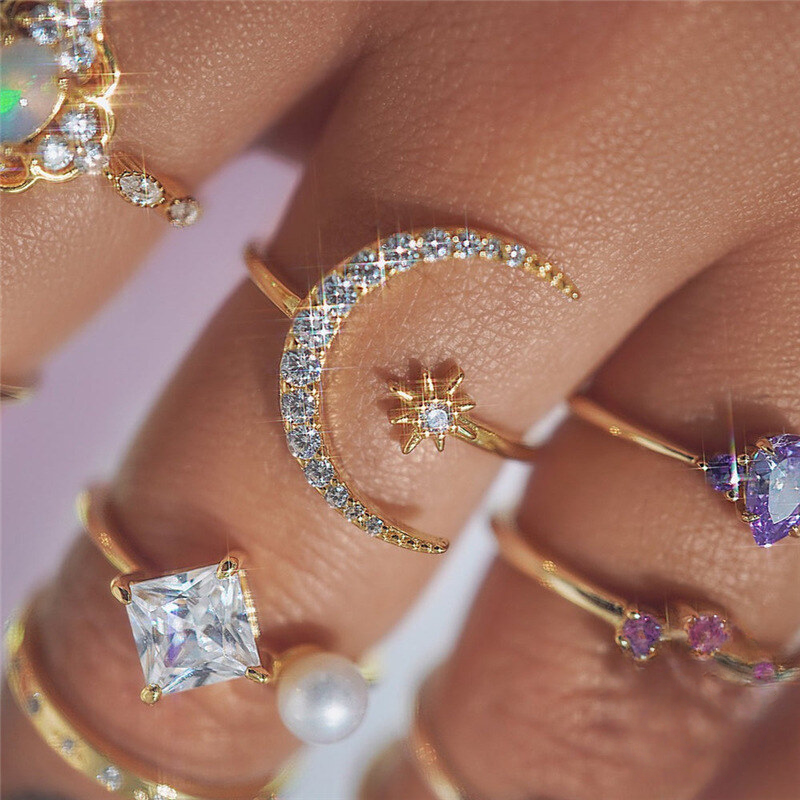 Close-up of various gold rings with gemstones on a pink background