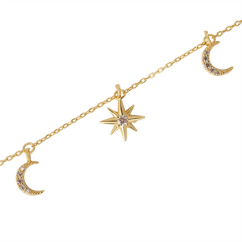 Gold anklet with star and moon charms on a white background
