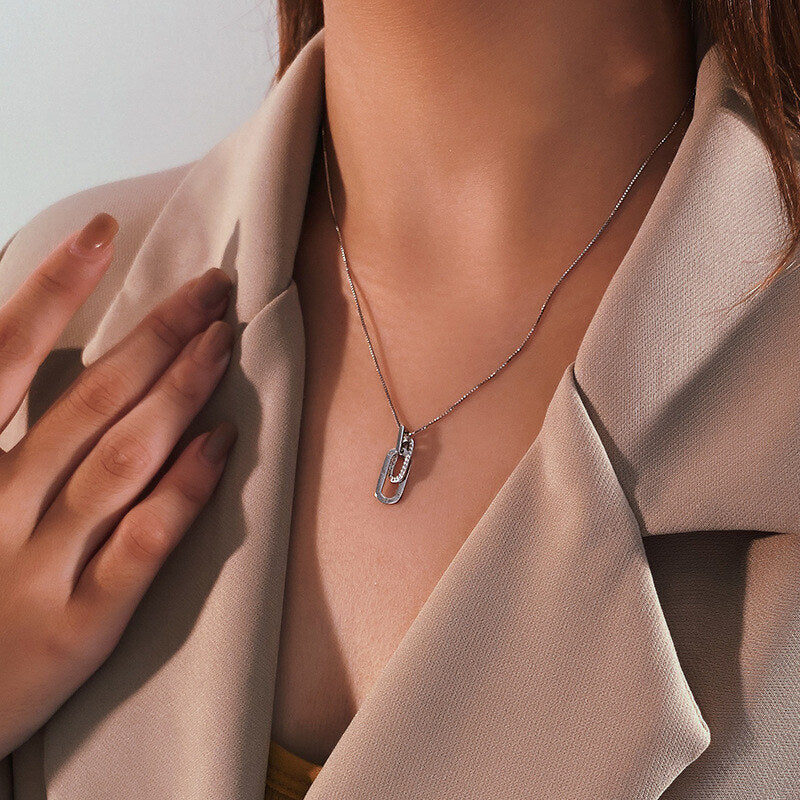 Necklace with a unique pendant worn by a person in a beige outfit.