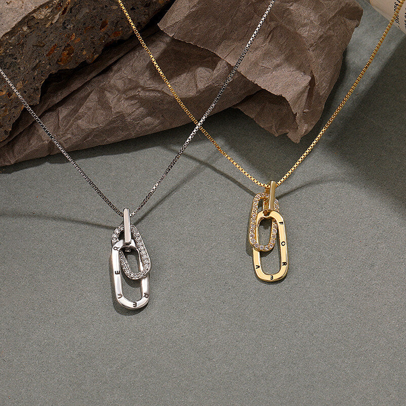Two necklaces with pendant pendants on a gray surface with brown paper.