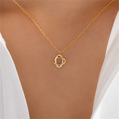 Gold necklace with a unique pendant on a person wearing a white top.