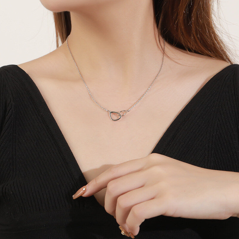 Necklace with a heart-shaped pendant worn by a person in a black top.