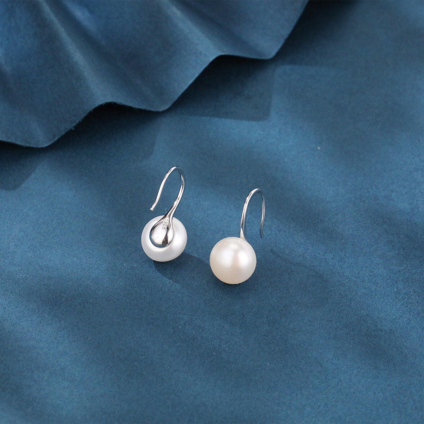Pearl earrings on a blue fabric background