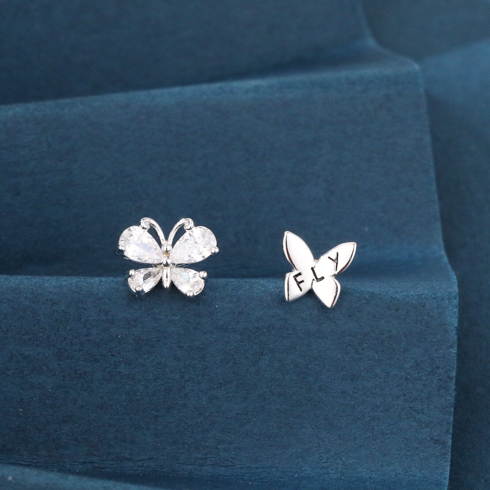 Butterfly-shaped earrings on a blue cushion