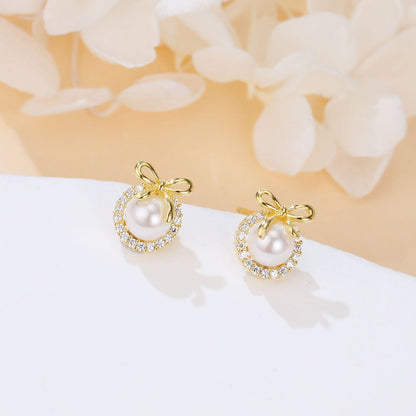 Gold earrings with pearls on a white surface with floral background
