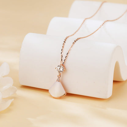 Rose gold necklace with a diamond pendant on a white stand against a beige background