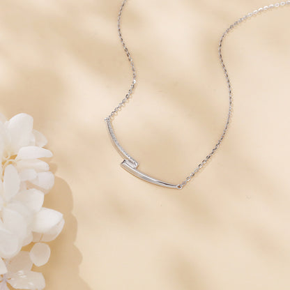 Silver necklace on a beige background with a white flower