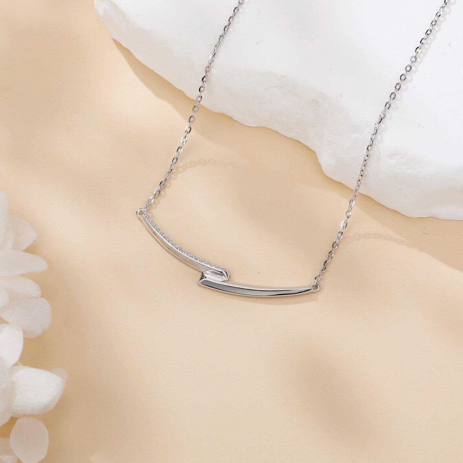 Silver necklace with a subtle design on a beige background